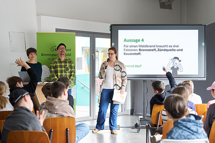 Pia steht vor einer Gruppe Schüler*innen und stellt ihren Faktencheck vor