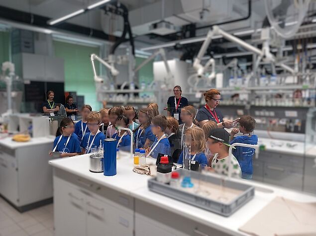 Viele Kinder in blauen T-Shirts, im Hintergrund Betreuerinnen in dunkelbauen Shirts