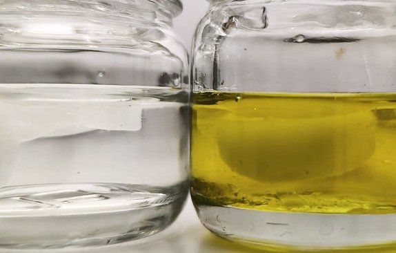 Links ist ein Glas Wasser mit einem Eiswürfel, rechts in Glas Öl mit einem gefrorenen Stück Öl